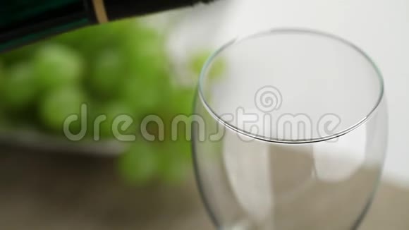 白葡萄酒和葡萄一起倒入桌子上的玻璃杯视频的预览图