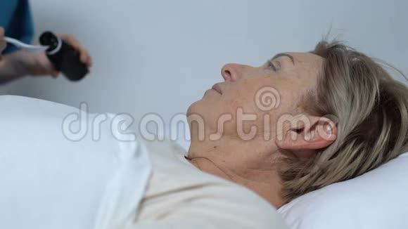 护士为躺在床上的老年女性病人提供糖浆住院治疗视频的预览图