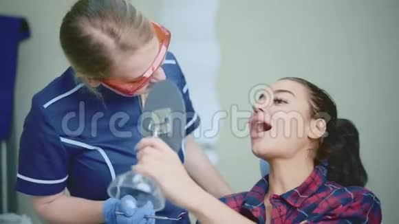 年轻女牙医为病人提供治疗结果视频的预览图
