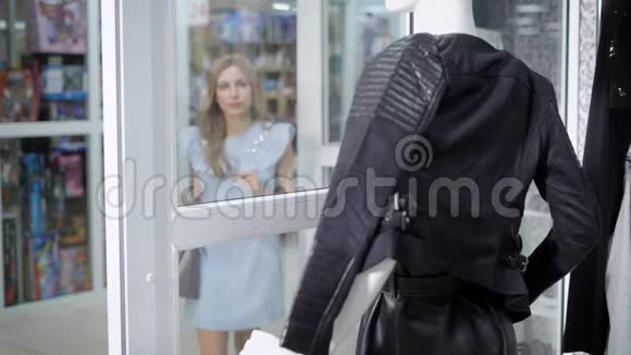 年轻的金发女人看到皮夹克在精品店展示视频的预览图