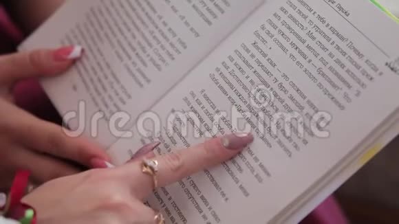 特写年轻女性的手戴着戒指漂亮的粉红色指甲和手腕上的花展示了书中写的建议视频的预览图