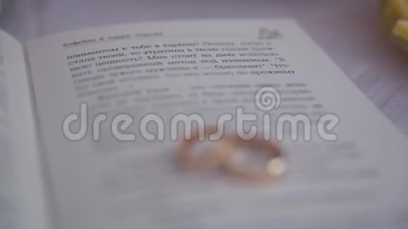 两枚金色结婚戒指躺在书页上上面写着文字视频的预览图