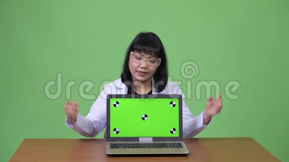 美丽的亚洲女医生戴着防护眼镜手提电脑竖起大拇指视频的预览图