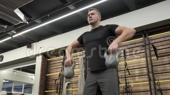 在现代健身房里用壶铃训练肌肉发达的年轻人视频的预览图