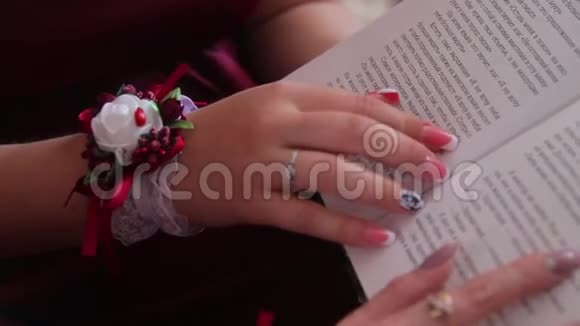 特写年轻女性的手戴着戒指漂亮的粉红色指甲和手腕上的花展示了书中写的建议视频的预览图