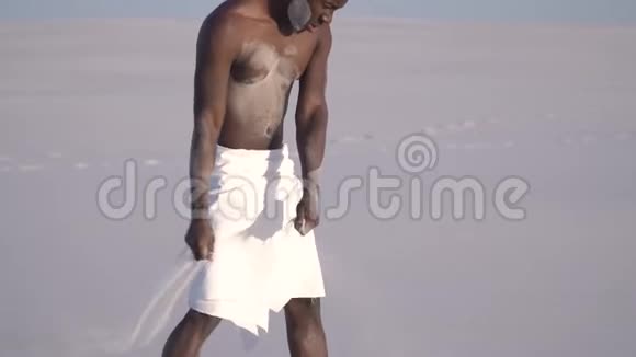 一个黑人在沙滩上从疲惫中摇曳一片无情的沙漠慢动作视频的预览图