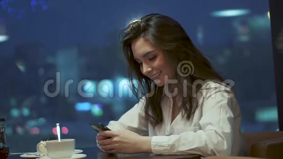 一个年轻的女孩在从手机里发信息的时候笑了笑视频的预览图