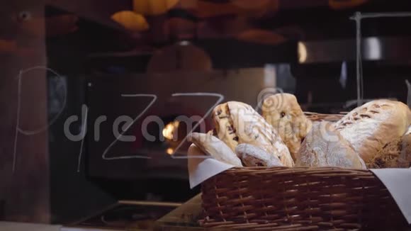 新鲜出炉的面包放在篮子里摆在现代餐厅的桌子上有燃烧的烤箱视频的预览图