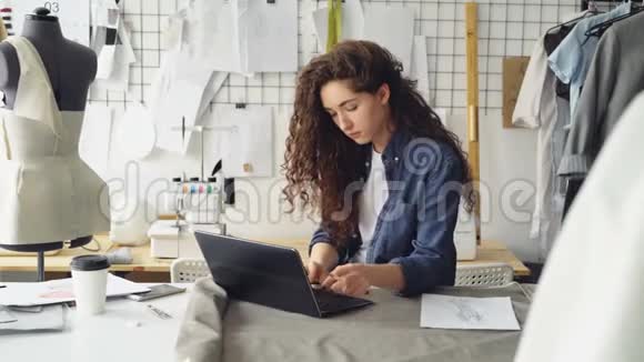 自雇的女裁缝正在现代轻车间用笔记本电脑办公女人正在打字看着视频的预览图