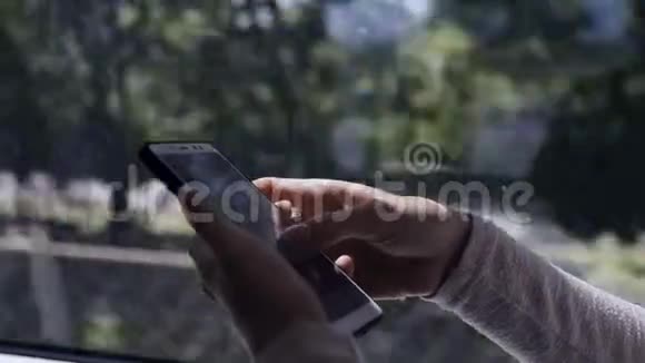 一个夏天美丽的女孩坐在城市的通勤列车上在智能手机上输入短信视频的预览图