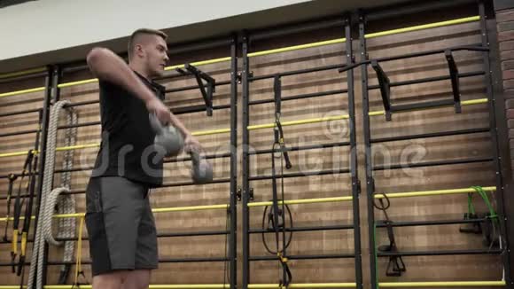 在现代健身房里用壶铃训练肌肉发达的年轻人视频的预览图