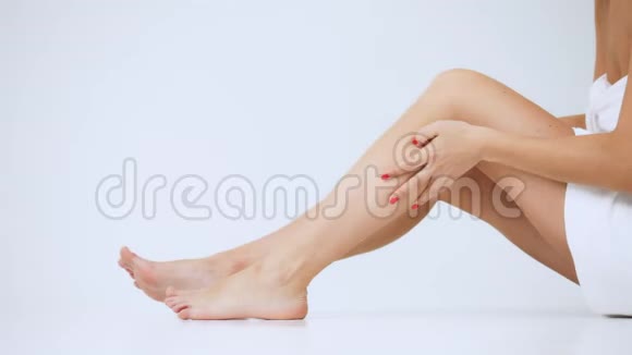 特写女人的腿女孩在艰难的一天后用清爽的奶油按摩她的腿孤立在白色的背景上视频的预览图