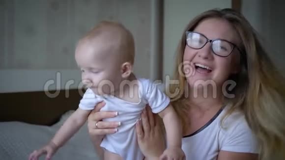 幸福的家庭戴着眼镜的快乐妈妈手里拿着婴儿在房间里看着镜头视频的预览图
