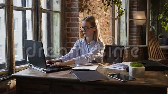 在现代办公工作场所的概念中漂亮的商业女孩在工作中使用文档和笔记本电脑视频的预览图