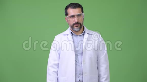 英俊的波斯胡子男医生戴着防护眼镜指着视频的预览图
