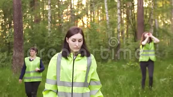 穿着绿色背心的志愿者穿过树林寻找失踪人员视频的预览图