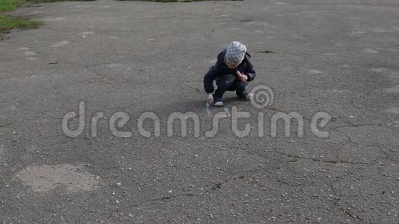 男孩用粉笔在沥青上画画视频的预览图