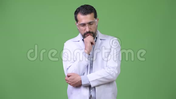 严肃的波斯胡子男医生戴着防护眼镜思考视频的预览图