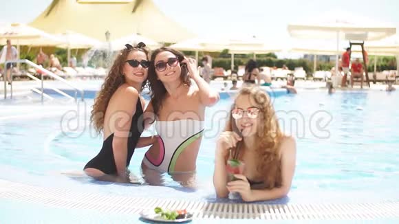可爱的女朋友与鸡尾酒杯冷在热带阳光下游泳池假期概念视频的预览图