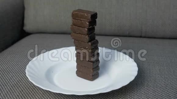 沙发上白色盘子上的巧克力糖果塔不健康饮食观念视频的预览图