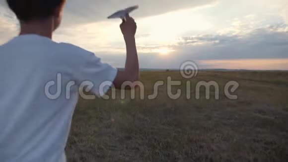 日落时分一个男孩在田野里跑扔了一架纸飞机幸福孩子的概念视频的预览图