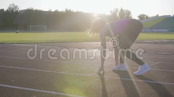 美丽的健身女孩从低起点跑到体育场训练中的年轻运动员慢动作视频的预览图