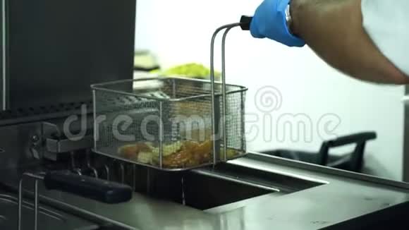 特写镜头一个戴着手套的厨师拿着一个特殊的格子来烤土豆烹饪土豆片炸薯条视频的预览图