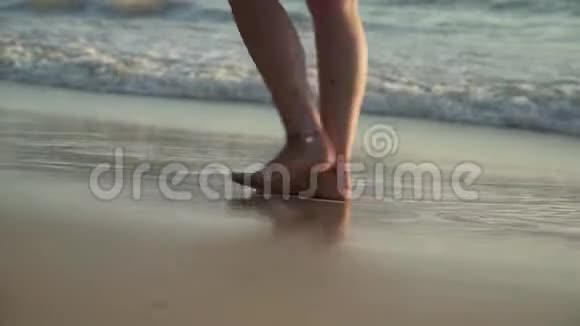 日落时分在海滩上散步的女人的双腿特写视频的预览图
