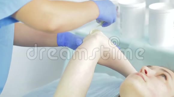 美容师的手在年轻女孩的手肘上涂上糖膏视频的预览图