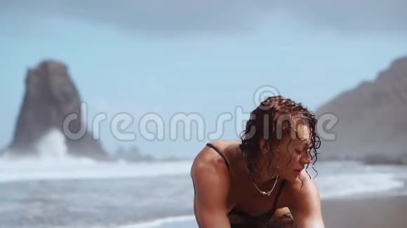 一位在海洋上从事体操的妇女坐在绳子上在水面附近的一座桥上背着海浪视频的预览图