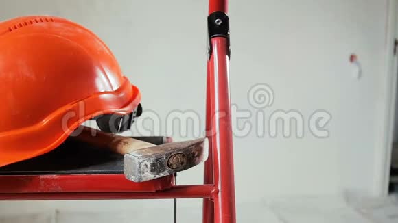 正在施工的建筑物或建筑物内的金属梯子上放置工作工具和红色头盔的特写慢动作视频视频的预览图