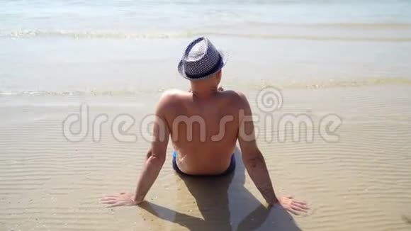 夏季生活方式高清视频美丽的年轻晒黑男子戴帽子享受生活坐在海滩上旅行的时间视频的预览图