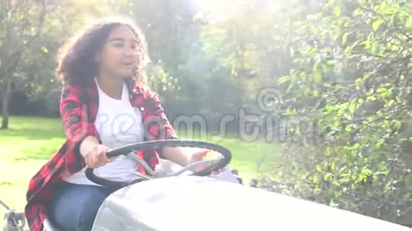 混血少女驾驶灰色拖拉机穿过阳光明媚的苹果园吃苹果视频的预览图