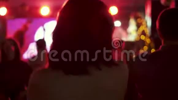 一个年轻女孩在一群人的背景下在迪斯科舞厅跳舞的肖像从后面看视频的预览图