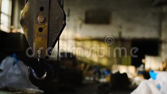 仓库里有起重机库存录像工业废弃仓库背景上悬挂的旧生锈起重机吊钩视频的预览图