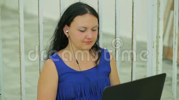 年轻女子坐在栅栏附近的街道上在笔记本电脑上工作视频的预览图