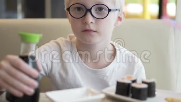 一个戴眼镜的男孩坐在咖啡馆的桌子旁视频的预览图