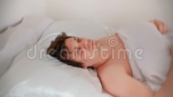 年轻的黑发帅哥躺在床上睡着了视频的预览图