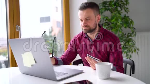 男人在家里用信用卡和笔记本电脑在线支付视频的预览图