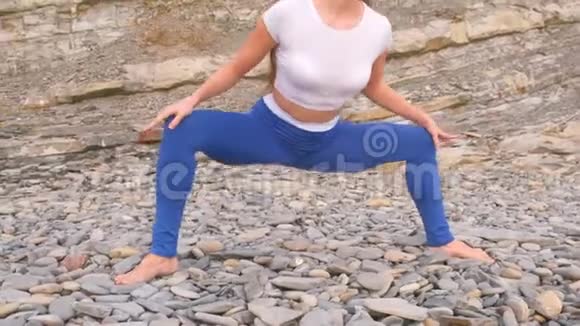 女孩在岩石背景上做呼吸练习时蹲着身体反射特写腿无法辨认视频的预览图