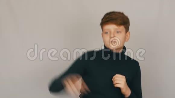 一个有趣的红头发和蓝眼睛的少年男孩的肖像在白色背景下在镜头前滑稽有趣地跳舞视频的预览图