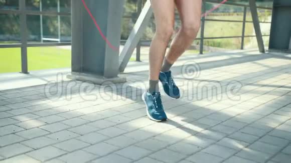 年轻运动员穿着舒适的运动服装在金属架附近的平台上的运动场上跳绳男孩在做什么视频的预览图