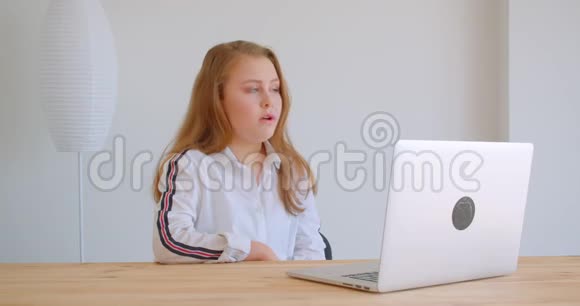 一位年轻漂亮的白种人女孩在公寓里的室内笔记本电脑上打了一个视频电话的特写照片视频的预览图