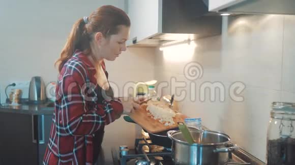 女人妈妈在厨房做饭的概念在平底锅里煮汤把洋葱倒进平底锅里就能烤面包了女孩视频的预览图