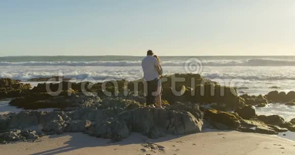 在海滩4k的岩石海岸站着一对夫妇视频的预览图