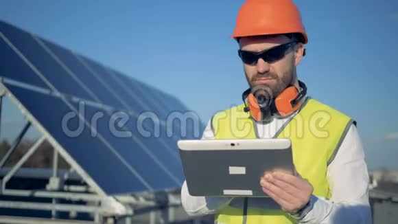 男施工员站在太阳能电池板旁边工作太阳能电池板收集太阳光视频的预览图