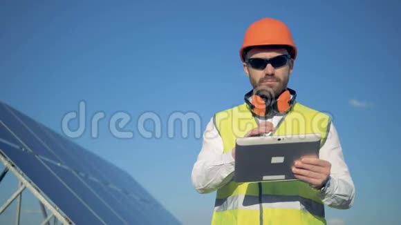 一名男性检查员站在太阳能电池板附近的电脑旁的工作过程视频的预览图