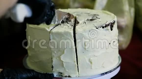 用小刀切上用白色奶油装饰的大巧克力蛋糕视频的预览图