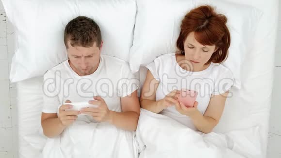 一对夫妻躺在床上看着智能手机在社交网络中交流并写下谎言的讯息视频的预览图