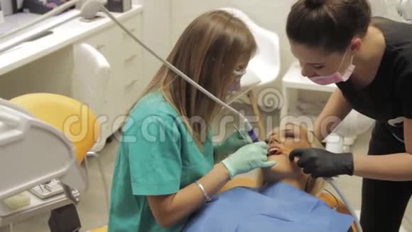 一位女牙医和她的助手正在为一位牙齿的病人工作视频的预览图
